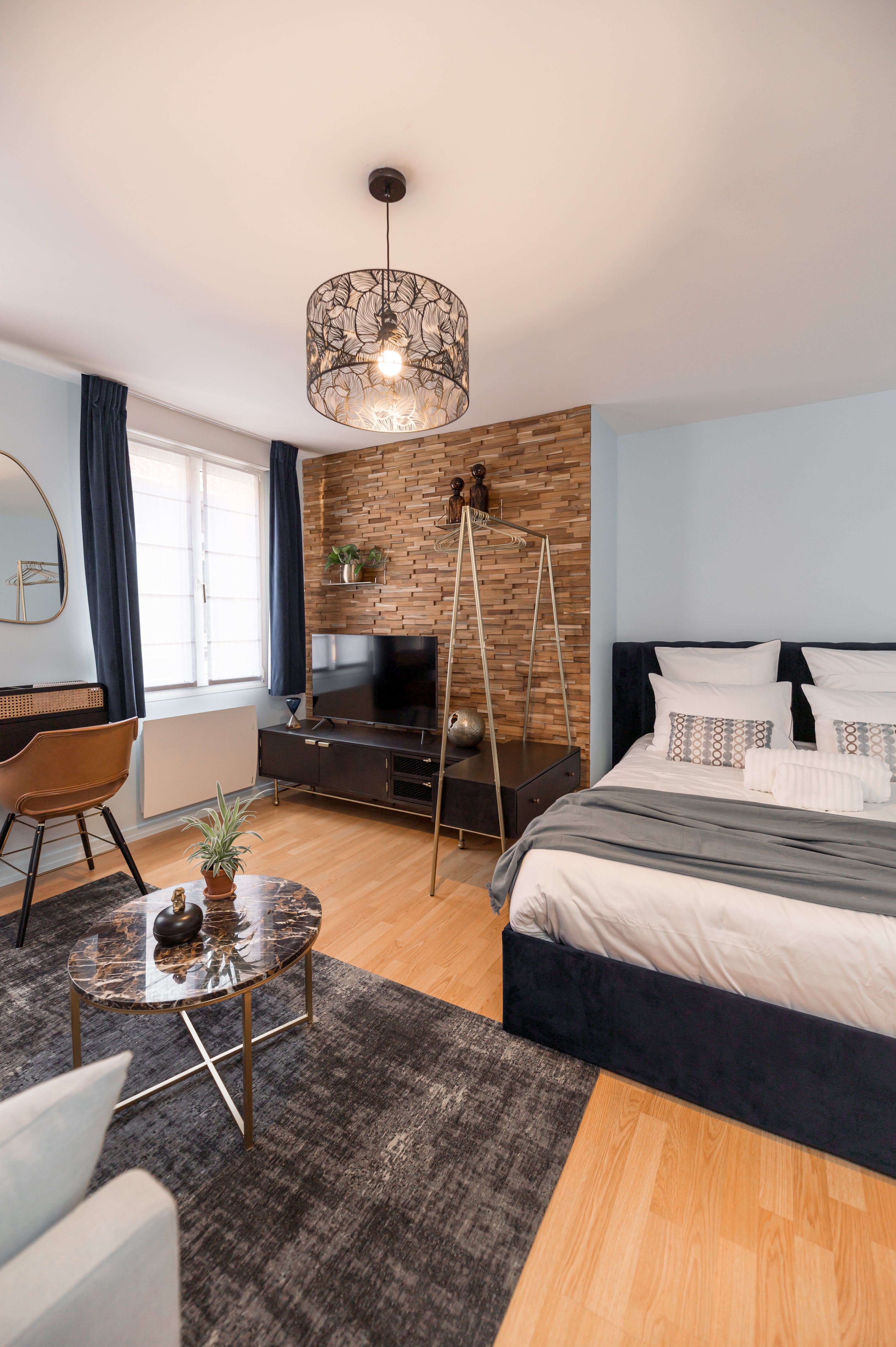 The Grand Escape — premium bedroom with genuine teak wall panelling, blue tones and crystal chandelier